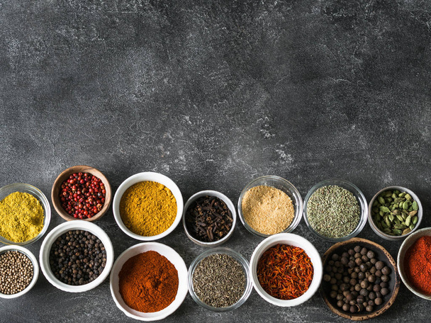 Various dry spices flat lay in small bowls on gray background. Top view, copy space - Φωτογραφία, εικόνα