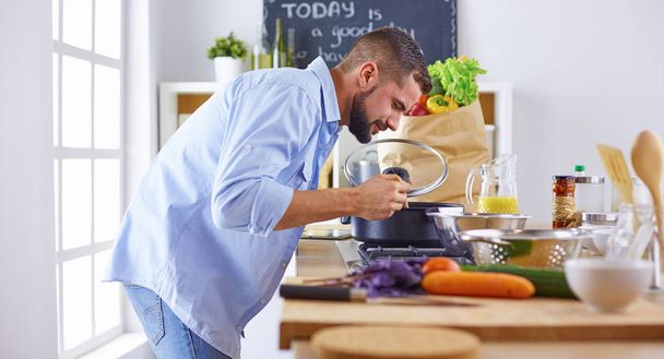 Usměvavá a sebevědomý kuchař stojící ve velké kuchyni ochutnávka  - Fotografie, Obrázek