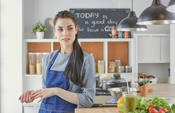 Щаслива молода жінка на кухні зі свіжими овочами на столі
 - Фото, зображення