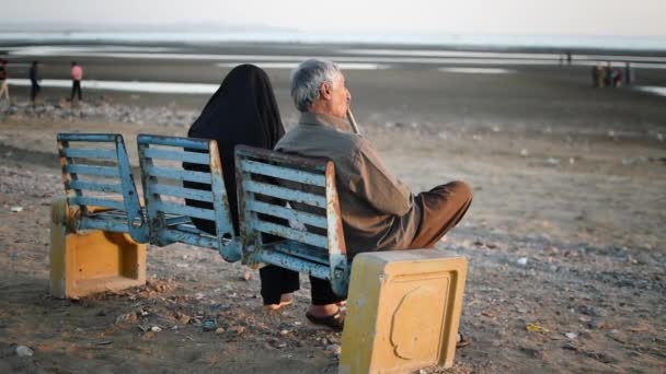 Ancianos pareja árabe sentarse en un banco y ver el mar
 - Metraje, vídeo