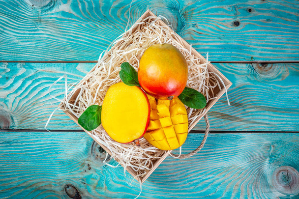 Famous Alphonso mango slices in a wooden box on a blue wooden background, Top view. Copy space - Foto, Bild