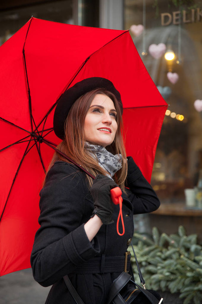 Πορτρέτο του όμορφη γυναίκα με κόκκινη ομπρέλα μπροστά από ένα καφενείο στην πόλη - Φωτογραφία, εικόνα