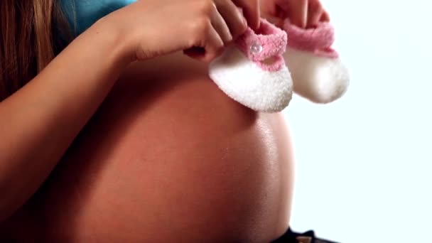 Pregnant woman's belly close-up: mom plays with children's shoes - Video, Çekim