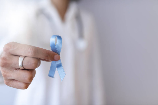 Female doctor holding blue cancer awareness ribbon - Фото, изображение