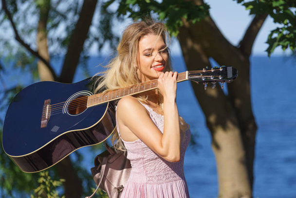 Woman playing acoustic guitar in park - Fotoğraf, Görsel