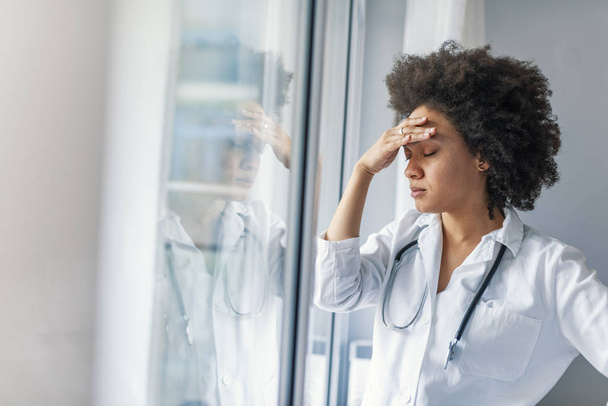 Tired stressed female doctor standing near window - Foto, Imagem