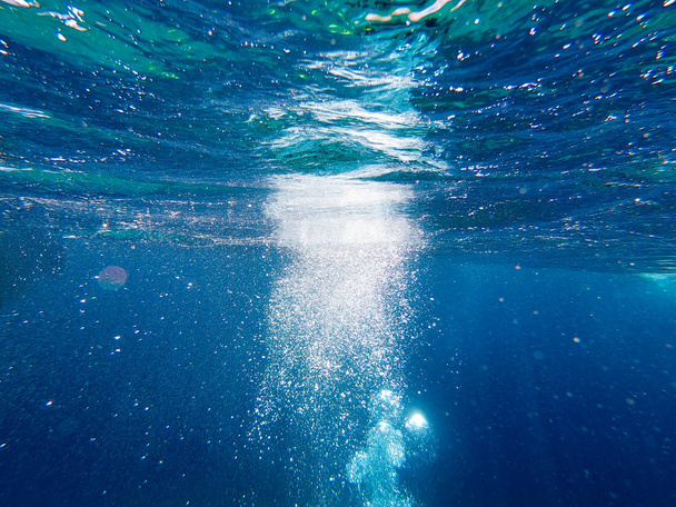 水の下の気泡が立ち上がる。海と海水の美しい食感。空中青の背景。水中写真. - 写真・画像