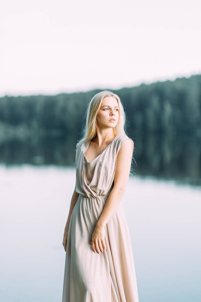 Girl in boudoir dress by the lake at sunset. Fees bride's on nature, harmony. Beautiful model, Russian girl with long hair - Valokuva, kuva
