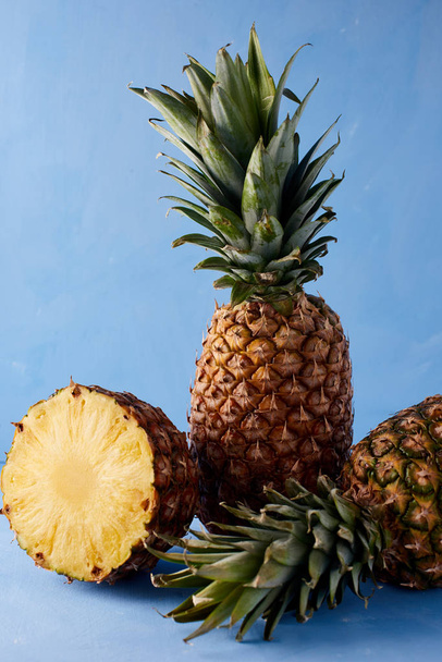 Ananas frische tropische Früchte auf blauem Hintergrund. Süße Zusammensetzung des Sommergetränks.  - Foto, Bild