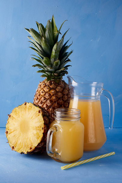 パイナップル ジュース、青の背景に新鮮なトロピカル フルーツ。夏の飲み物の甘い組成.  - 写真・画像