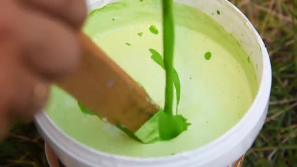 In white acrylic paint pour and mix the green color with a wooden stick - Felvétel, videó