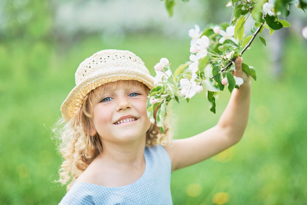 girl sniffing flowers of apple orchard. garden with flowering trees - Foto, Imagem