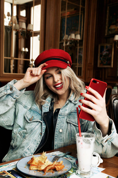 beautiful woman with blond hair in casual clothes and red hat si - Фото, зображення