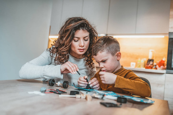 Mother helping son with electronic project in building robot - Foto, immagini