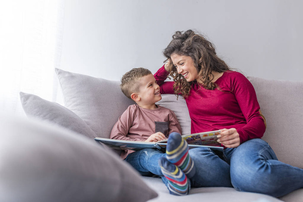 Young woman and little son reading book on sofa - Foto, Imagem