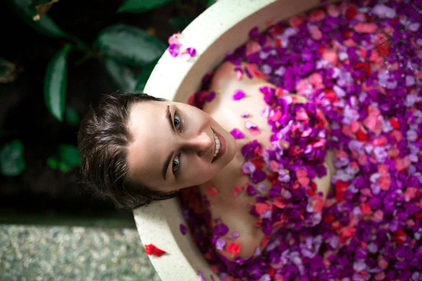 Beauty young Woman relaxing in outdoor bath with tropical flower - Foto, Imagen