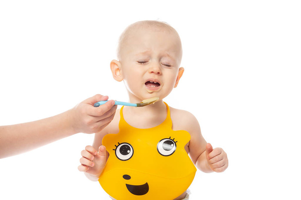 Il bambino non vuole mangiare. Bambino in posa in bavaglino giallo Isolato su fondo bianco. famiglia, cibo, mangiare e concetto di persone - Foto, immagini