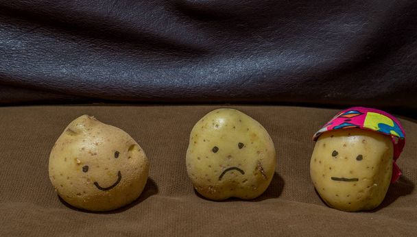 Trois pommes de terre fraîches sur un canapé brun concept paresseux - image avec espace de copie au format paysage
 - Photo, image