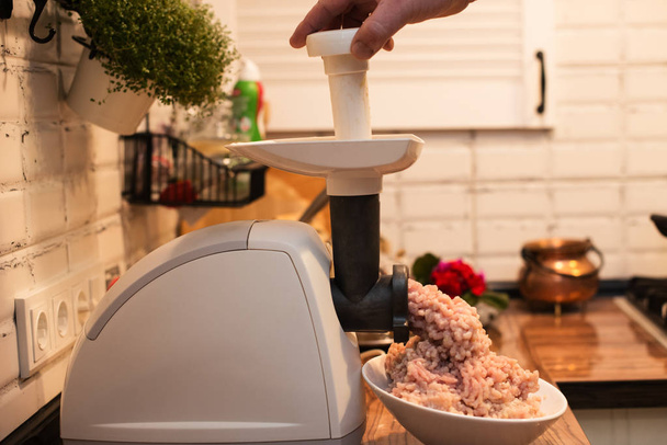 Hackfleisch in einem elektrischen Fleischwolf auf dem Küchentisch kochen - Foto, Bild