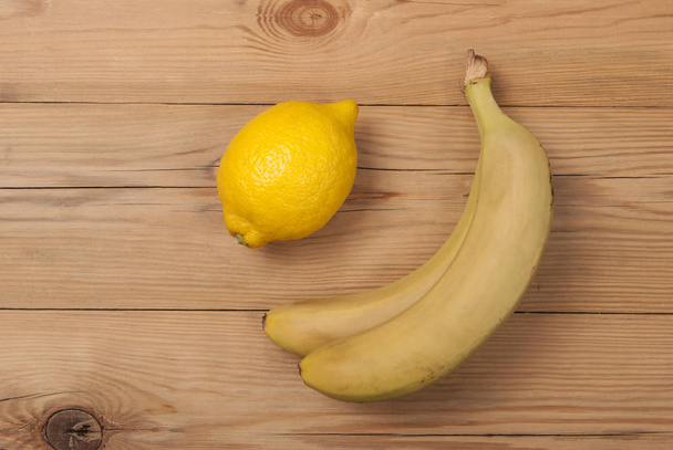 Lemon and bananas on a wooden background. View from above . - Photo, Image