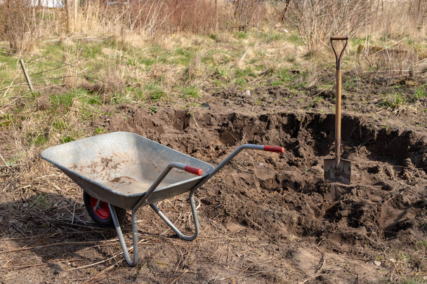 Wheelbarrow and spade in the garden. Cleaning works in the garde - Foto, immagini