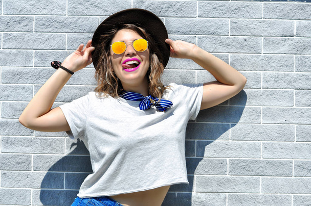 City vibes καλοκαίρι. Ηλιόλουστο lifestyle μόδα πορτρέτο όμορφη νεαρή χαμογελαστό γυναίκα διασκέδαση φορώντας γυαλιά ηλίου μοντέρνο ντύσιμο πάνω από γκρι φόντο  - Φωτογραφία, εικόνα