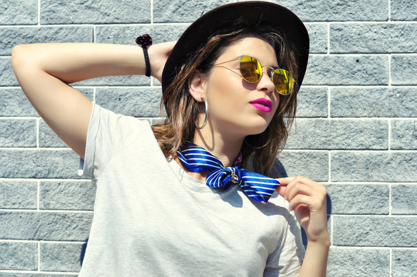 Summer city vibes. Sunny lifestyle fashion portrait pretty young woman wearing trendy outfit sunglasses pink lipstick over grey background   - Photo, Image