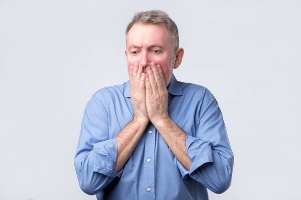 Senior homme couvre la bouche et regarde désespérément
 - Photo, image