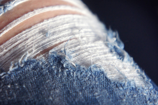 gaten op jeans, draden uitsteken versleten spijkerbroek - Foto, afbeelding