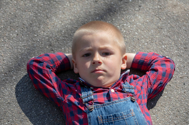 bambino sdraiato sul pavimento sul retro, guardando lontano. pensieroso
 - Foto, immagini