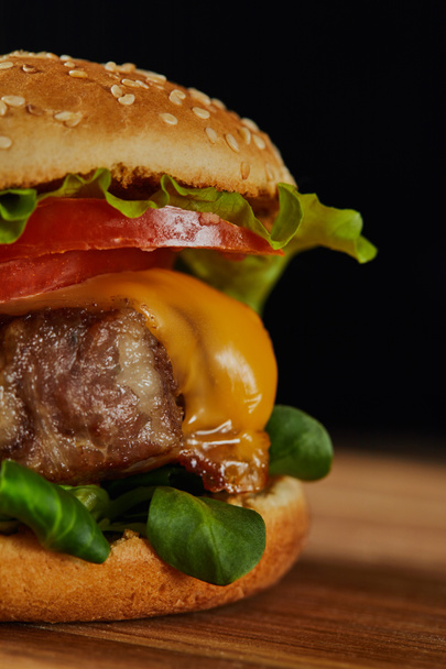 close up of delicious meat burger with cheese, greenery, tomatoes and sesame - 写真・画像