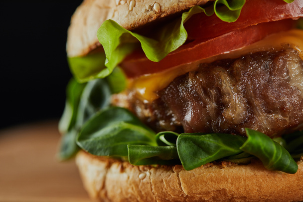 close up of tasty meat burger with cheese, greenery and tomatoes  - Photo, Image