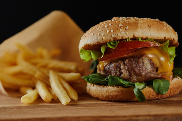 selective focus of french fries and tasty burger with meat isolated on black - Photo, Image