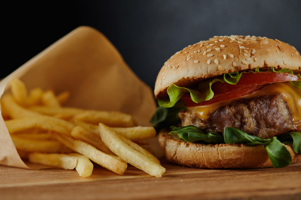 delicious burger with meat and french fries on wooden surface - Photo, Image