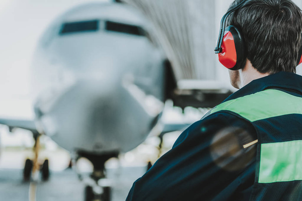 Employee in red headphones working at aerodrome - Фото, зображення