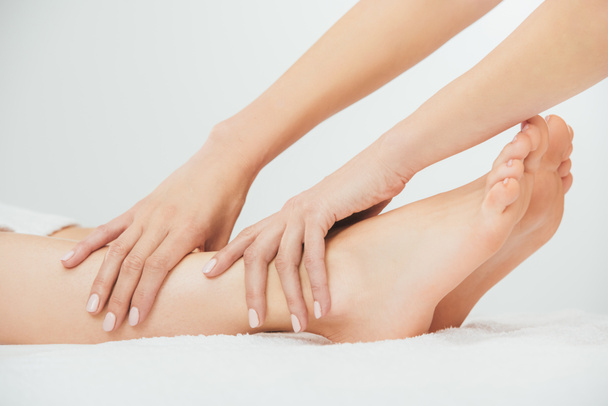 oříznutý pohled na maséra, který provádí masáž nohou k dospělé ženě v lázních - Fotografie, Obrázek
