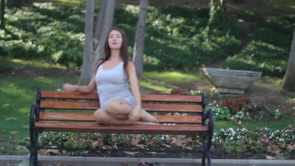 Park. A girl sits on a bench - Filmati, video