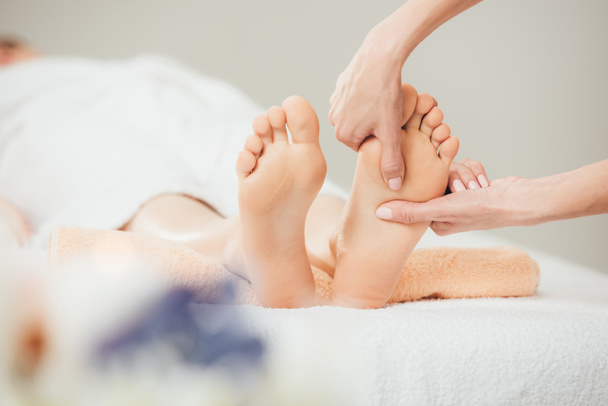 selective focus of masseur doing foot massage to adult woman in spa - Foto, Imagem