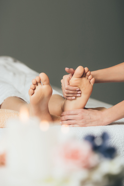 partial view of masseur doing foot massage to adult woman in spa - Fotó, kép
