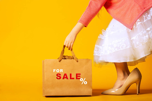 little girl in oversized shoes, taking a paper bag with an inscription sale - Foto, Bild