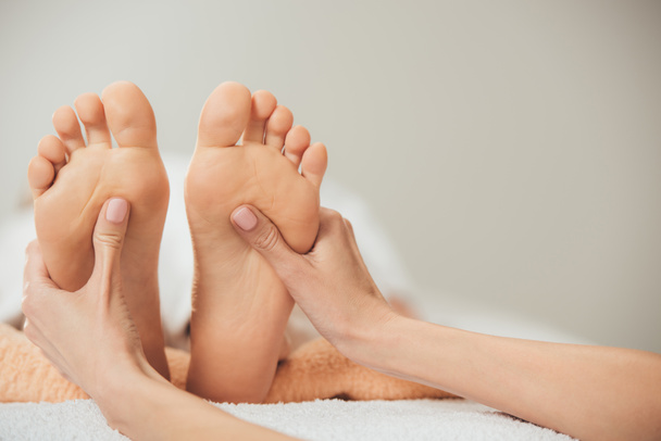 partial view of masseur doing foot massage to adult woman in spa - Zdjęcie, obraz