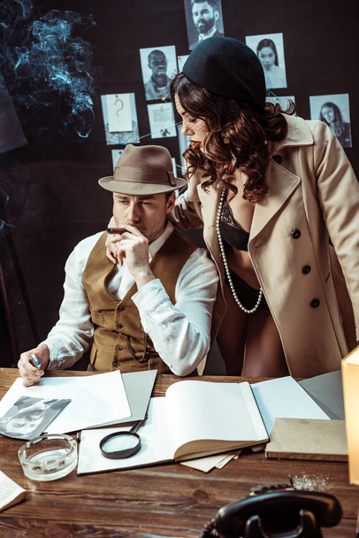Mujer sexy en ropa interior y abrigo de trinchera seduciendo detective en la oficina
 - Foto, Imagen