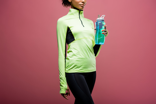 Kısmi izole kahverengi üzerine spor şişe ile parça ceketli Afro-Amerikan sporcumuz görünümünü - Fotoğraf, Görsel