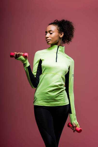 beautiful african american sportswoman training with dumbbells isolated on brown - Valokuva, kuva