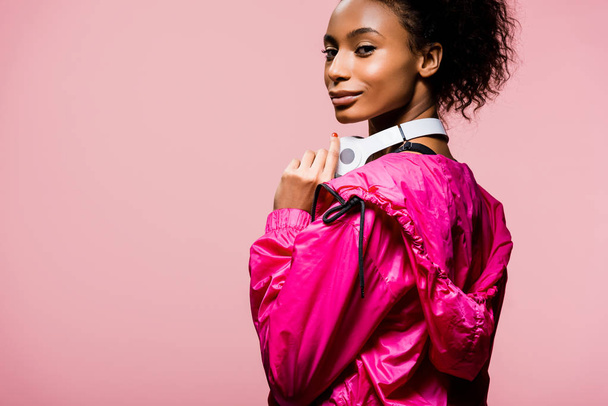beautiful african american sportswoman with headphones looking at camera isolated on pink with copy space - Foto, Imagem