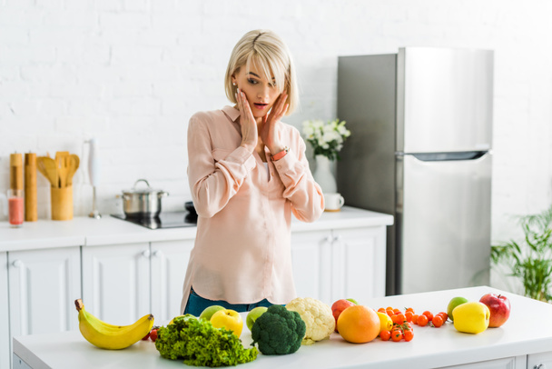 surprised blonde pregnant woman looking at fruits and vegetables  - Fotografie, Obrázek