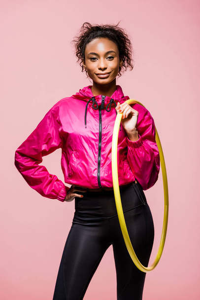 beautiful african american sportswoman looking at camera and holding hula hoop isolated on pink - Fotoğraf, Görsel