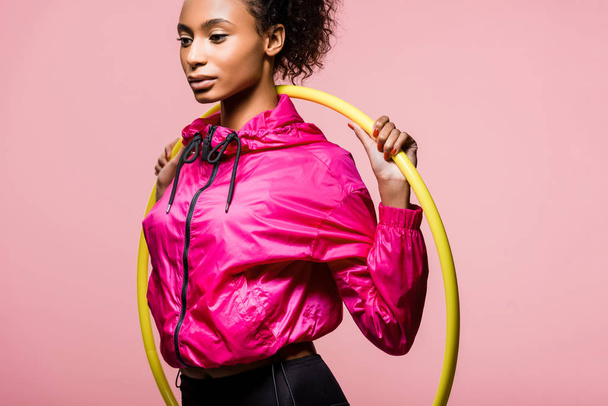 attractive african american sportswoman posing with hula hoop isolated on pink - 写真・画像