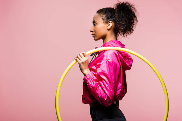 side view of beautiful african american sportswoman posing with hula hoop isolated on pink with copy space - Valokuva, kuva