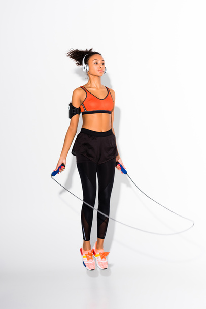 sportive afro-américaine sportive en casque d'entraînement avec corde à sauter sur blanc
 - Photo, image